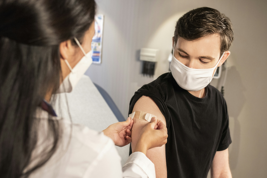 Health Care Provider Places Bandage on Arm
