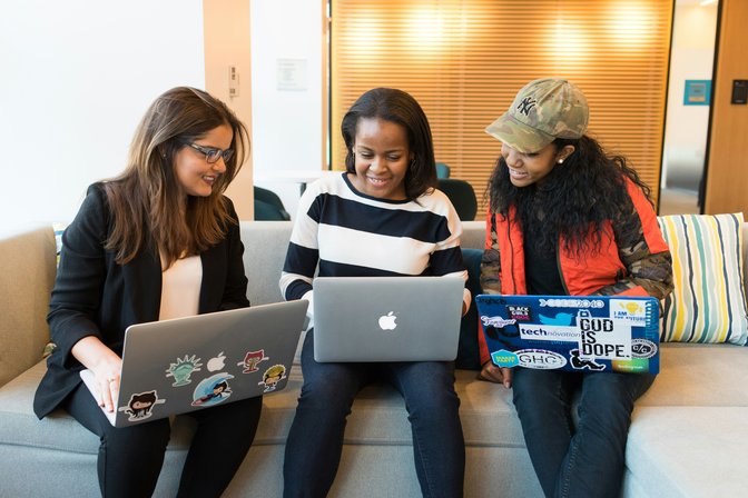 Three Women Sitting on Sofa With Laptops