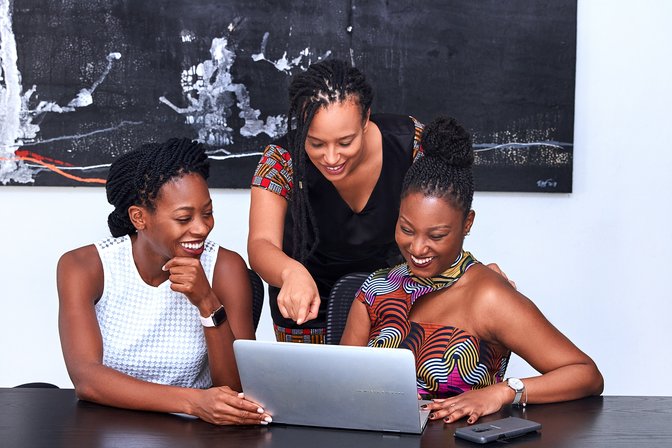 Three Ladies Smiling Around a Laptop